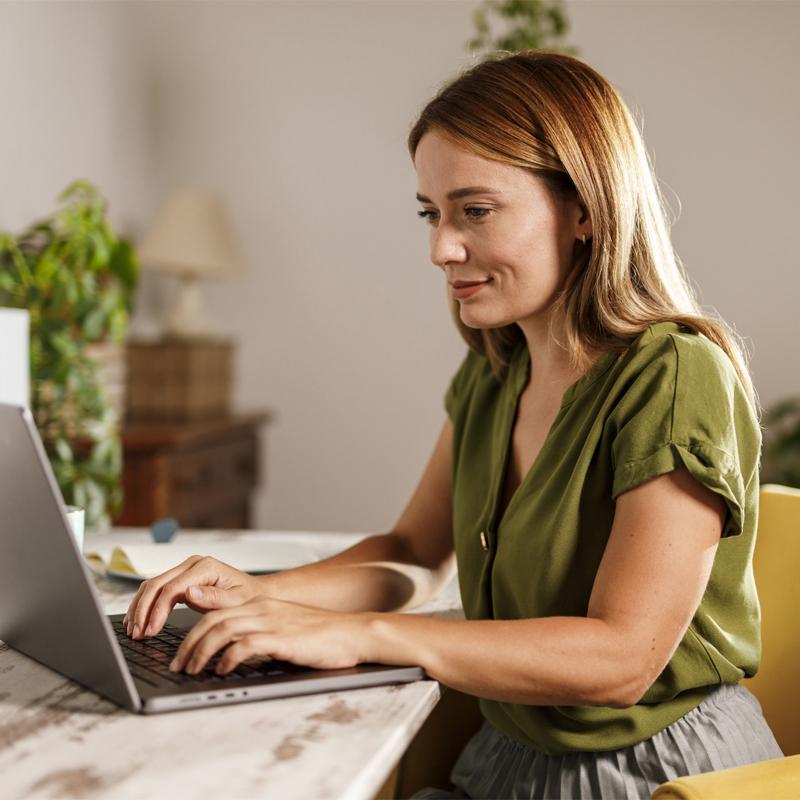 Portrait of diligent mid adult woman using laptop when working on a project, at home office.