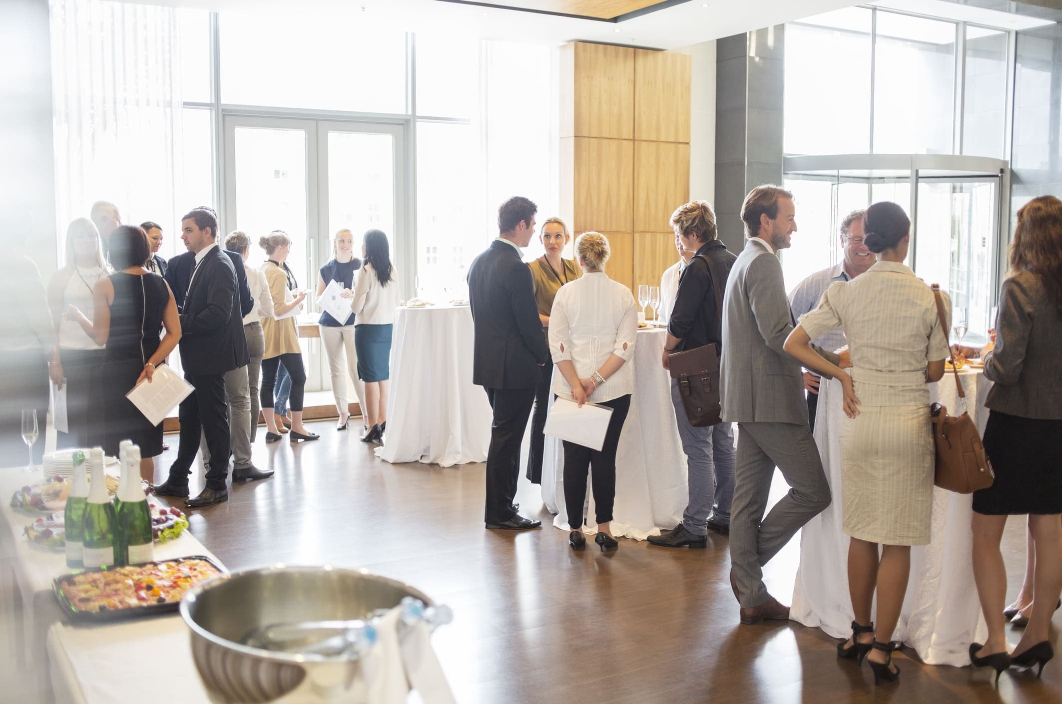 Group of conference participants standing in lobby of conference center, socializing during lunch break